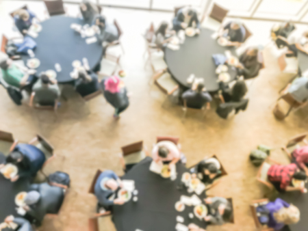 Blurred motion top view lunch break at conference meeting. Defocused delegates networking on round banquet tables, catering food buffet. Diverse group of participants on business, entrepreneurshipの写真素材