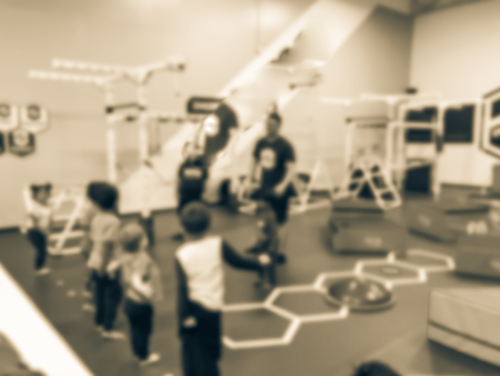Blurry background coach and kids at children gym class in USA