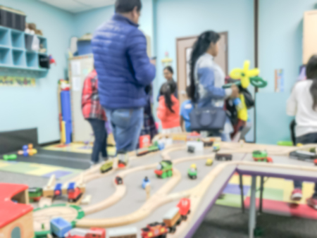 Blurred motion kids and parents enjoy playing toys car track racing indoor. Abstract background diverse, multicultural group of people gathering together near Dallas, Texas, USAの写真素材