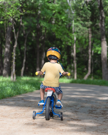 Back view of healthy Asian kid riding bicycle in the American parkの写真素材