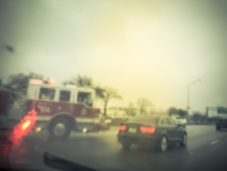 Blurred motion road accident on wet rainy day near Dallas, Texas, USA. Fire trucks and police car support and rescue injured people. Bad driving condition and severe weather conceptの写真素材
