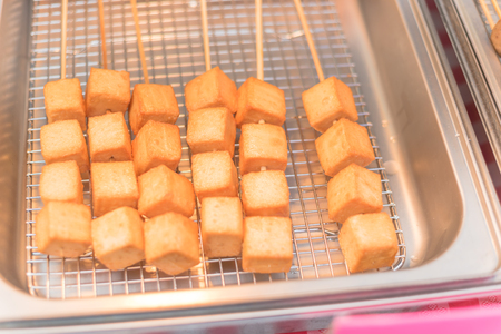 Skewers of fried tofu cubes on frying panの写真素材