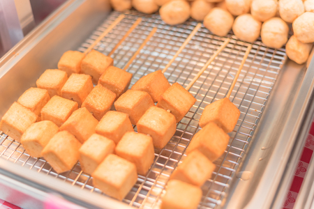 Skewers of fried tofu cubes on frying panの写真素材