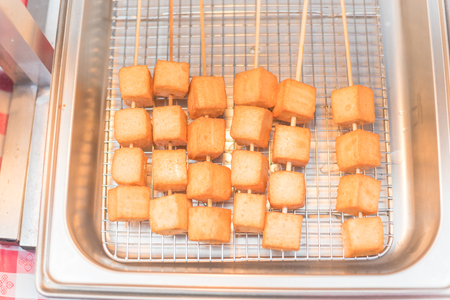 Skewers of fried tofu cubes on frying panの写真素材