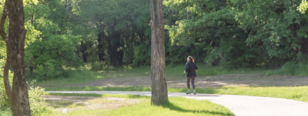 Panoramic back view of healthy Caucasian lady walking in the park in USA