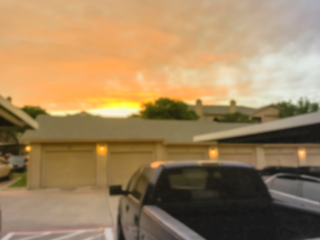 Blurry background typical apartment complex with detached garage and covered parking lots at sunset