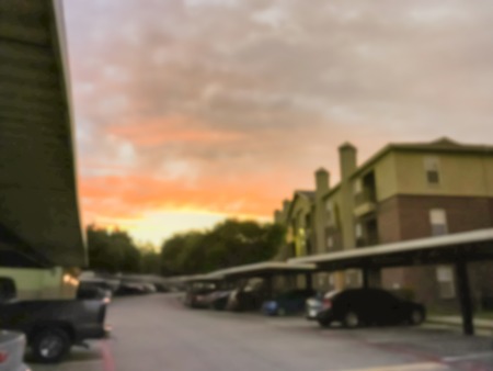 Blurry background typical apartment complex with detached garage and covered parking lots at sunset