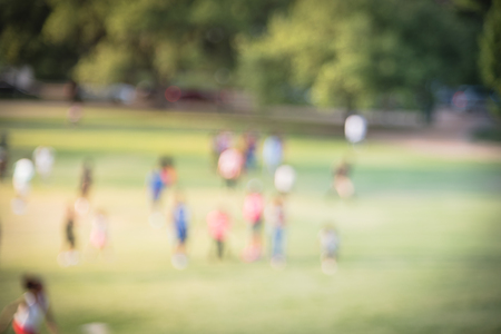 Blurry background children running on grass lawn at the park in Americaの写真素材