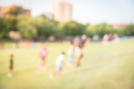 Blurry background children running on grass lawn at the park in Americaの写真素材