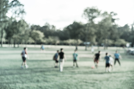Filtered image blurry background Latin America boys playing soccer at park during sunsetの写真素材
