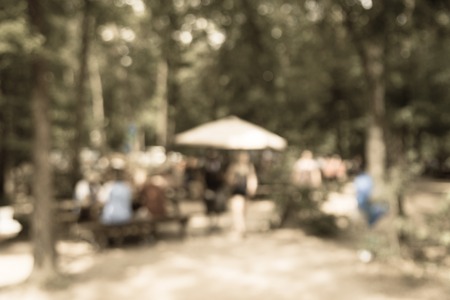 Vintage tone blur image group of people hanging out at semi forest, wooded area of craft brewery in Conroe, Texas, US. Beer garden fill with picnic tables, long benches setup under tall oak treesの写真素材