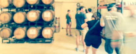 Panorama view modern beer plant brewery , stack of barrels in cellar, stainless steel brewing equipment and customers line up to taste craft in taproom. Production vats, fermentation interiorの写真素材