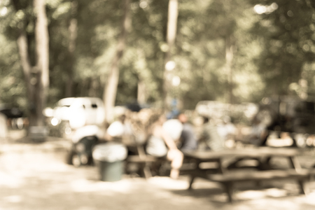 Vintage tone blur image group of people hanging out at semi forest, wooded area of craft brewery in Conroe, Texas, US. Beer garden fill with picnic tables, long benches setup under tall oak treesの写真素材