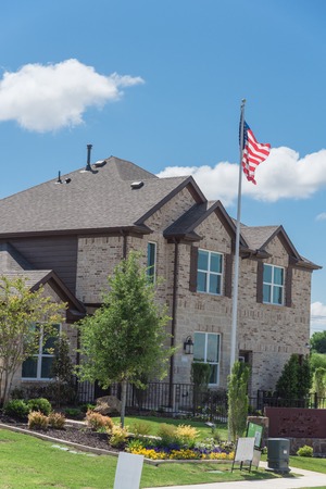 Brand new two story house with attached garage in new development neighborhood near Dallas, Texas, USA. Model house with American flagの写真素材