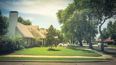 Corner house in quite neighborhood with tall trees canopy and pathway sidewalkの写真素材