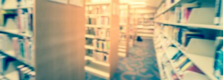 Panorama view blurred wide perspective view aisle of bookshelf with reading step stool at public library in America. Continuing education conceptの写真素材