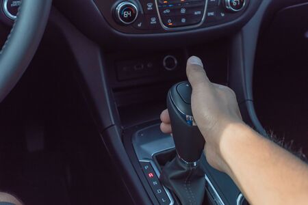 Male hand holding automatic gear stick of a modern car