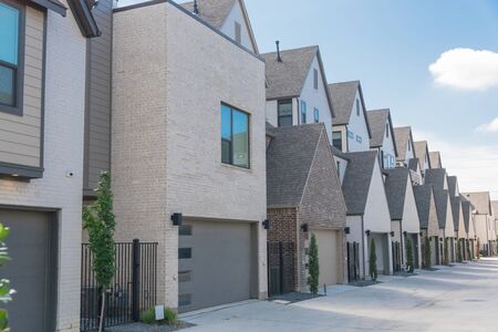 Row of garages from modern three story houses in North Dallas, Texas. Large back alley of new development residential community with metal fence gate and well trim landscapeの写真素材