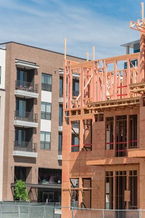 Close-up new development neighborhood with rental units under construction in North Dallas, Texas, USA. Wooden framework of five-story apartment complex with large patio near completed buildingsの写真素材