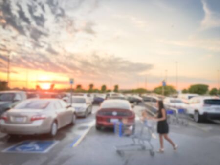 Motion blurred customer with shopping cart walking at parking lots of grocery store near Dallas, Texas, America. Beautiful and dramatic sunset cloudの写真素材
