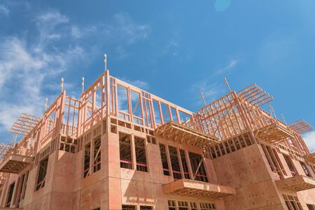 Low angle view of modern condominium building with large patio under construction near North Dallas, Texas, America. Wooden house with timber framing, truss, joist, beam close-up under cloud blue skyの写真素材