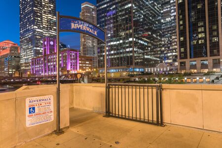 Entrance to Chicago Riverwalk at blue hour. Picturesque river with shiny skyline view, outdoor bars and restaurants for eat, drink and playの写真素材