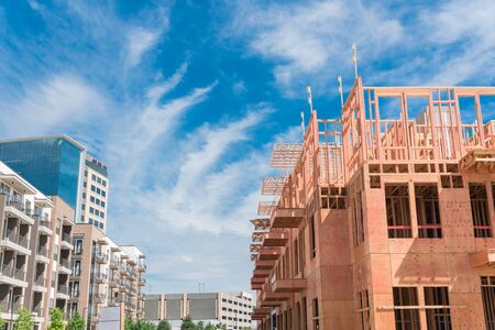 New development neighborhood with rental units under construction in North Dallas, Texas, USA. Wooden framework of five-story apartment complex with large patio near completed buildingsの写真素材