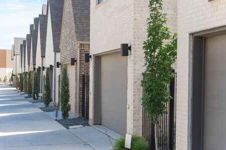 Row of garages from modern three story houses in North Dallas, Texas. Large back alley of new...