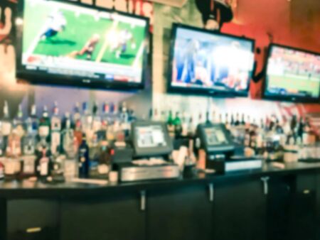 Blurred motion a bar counter of compact restaurant in Seattle, Washington, USA. Variety of beer tap and liquors, row of hanging big flat TV screens with customer diningの写真素材