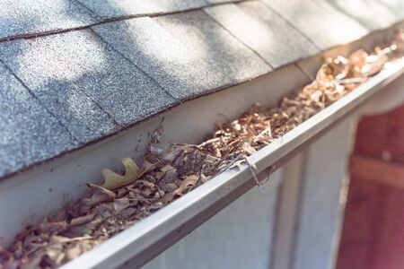 Top view close-up gutter of residential house full of dried leaves and dirty need to clean-up. Gutter cleaning and home maintenance conceptの写真素材