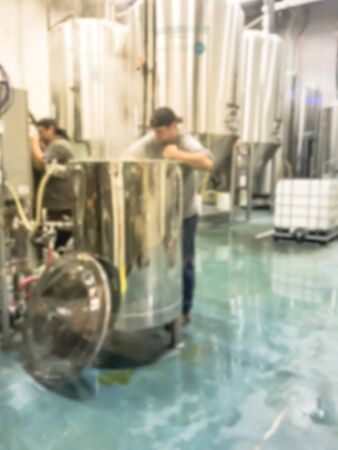 Motion blurred adult brewery workers with cap stirring beer in container while working at local brewing company in North Dallas, Texas, America. Spent grain at brew houseの写真素材