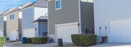 Panoramic back alley of residential neighborhood line of two-car garage door colorful houses near...