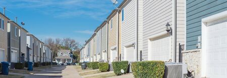 Panoramic back alley of residential neighborhood line of two-car garage door colorful houses near...