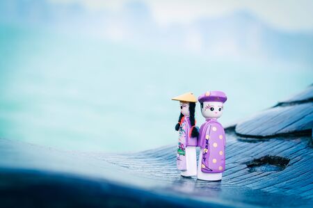 Handicraft Vietnamese magnetic wooden puppets in traditional costumes with natural ocean background....