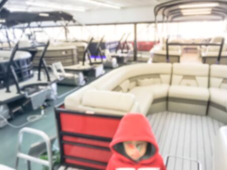 Abstract blurred Asian toddler boy in warm clothes at large dealer selling variety of new and used boats near Dallas, Texas, USA. Recreational boat buying and servicing conceptの写真素材