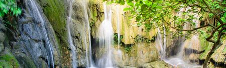 Panorama view jungle waterfall cascade Thac Voi at tropical rainforest in Thanh Hoa province, Vietnam. Current stream gushing through cascade tiers into emerald pond with by mature treesの写真素材