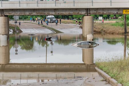 Unidentified people witness swamped car by flood water near downtown Houston, Texas.