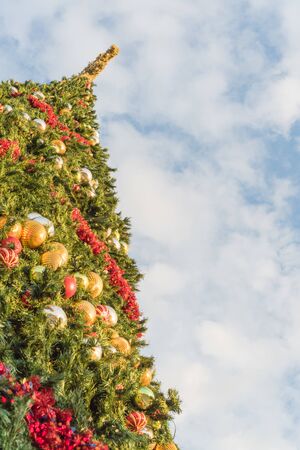 Lookup view 60 foot Christmas tree with snowflake top, ornament balls and efficient LED lights. Typical Xmas decoration at upscale shopping center in Texas, America. Low angle view blue cloud skyの写真素材