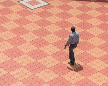Asian person walking along patio tiles outdoor sing Singapore directly above viewの写真素材