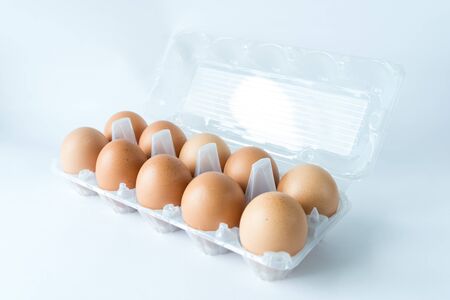 Open transparent plastic tray with ten of organic brown eggs on plastic egg carton isolated on white...