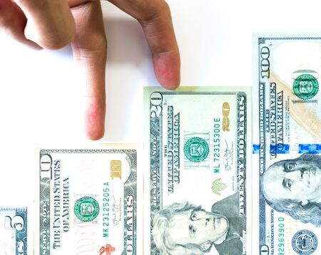 Asian male fingers go upward the stairs made from various United States Dollars banknotes, bills isolated on white background. Business growth conceptual backgroundの写真素材