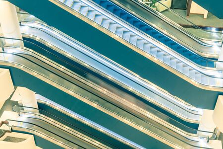Toned photo escalator stack inside a modern office space on each floor. Typical scene at commercial...