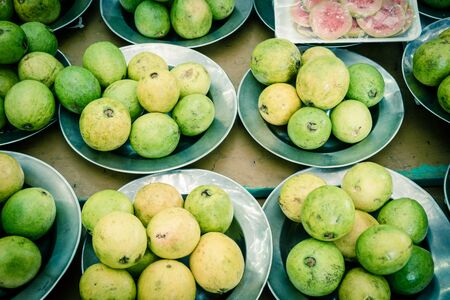 Pre-pack slices cut of red guavas and pile of fresh raw aluminium trays on display at local fruit...