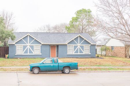 Residential street with typical bungalow house and parked cars under winter snow cover near Dallas, Texas. Middle class residential home in America.の写真素材