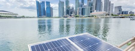 Panorama close-up solar panel with modern city and skyscrapers in background in Singapore. Cloud blue sky.の写真素材