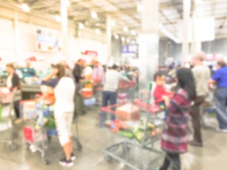 Blurred image cashier with long line of people at check-out counter of wholesale store in America. Customers paying with credit card to store clerks, full cart of groceries. Cashier register conceptの写真素材