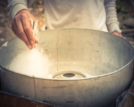 Close-up Asian hand rolling cotton candy in floss machine in Vietnam. Process of street food makingの写真素材