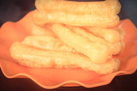 Toned image orange plate of Youtiao or cakwe or Chinese cruller, fried breadstick, fritters, oil...