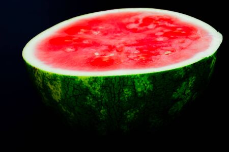 Half cut of organic watermelon isolated on black background. Summer refreshment fruit with clipping path and copy space.の写真素材