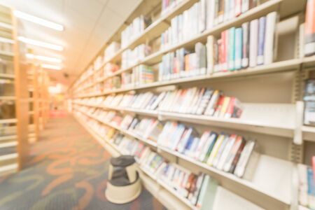 Blurred, wide perspective view aisle of bookshelf with reading step stool at public library in America. Continuing education concept.の写真素材